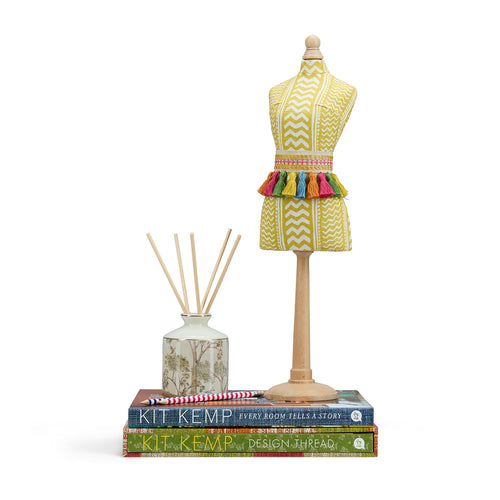 This mini mannequin in joyful design, upholstered in a sunny yellow "Tweak" fabric that radiates warmth. The standout feature is the rainbow coloured fringed belt. Its bright palette and playful tassels never fail to delight, making it a perfect "conversation starter" for a bedside table or mantle.