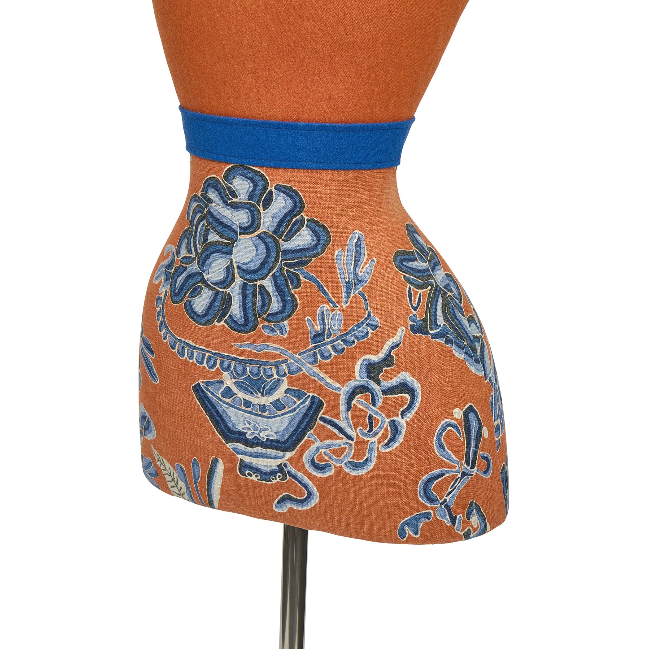 Mannequin wearing an orange apron with blue floral and geometric patterns on a white background