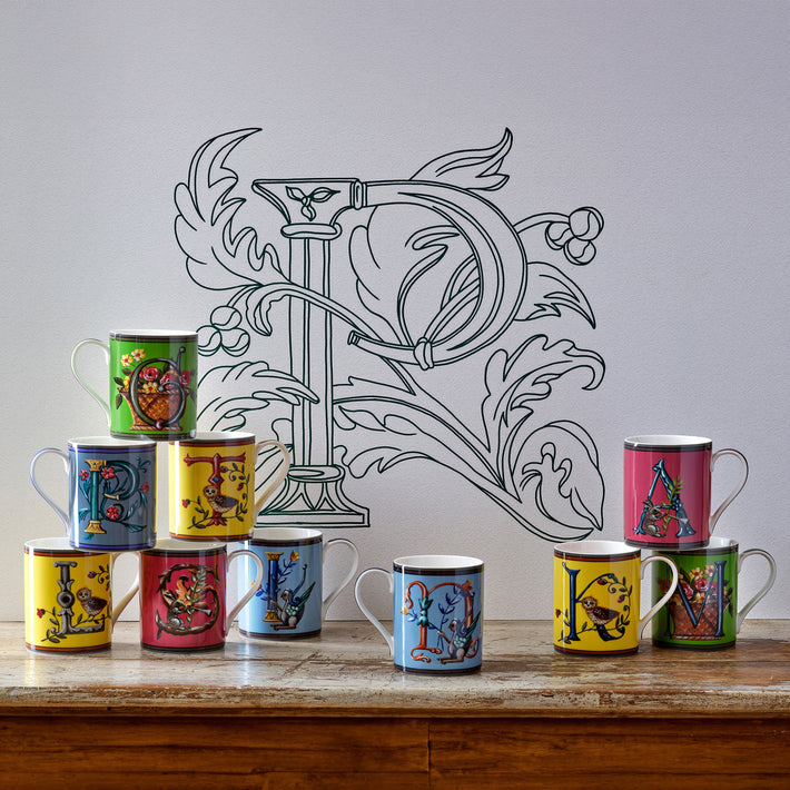 Alphabet mugs piled on a table.