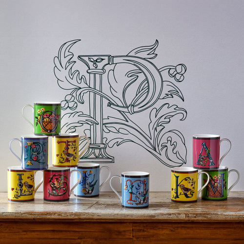 Alphabet mugs piled on a table.