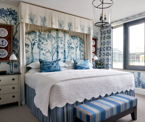 Firmdale bedroom featuring the Tall Trees blue headboard, and wallpaper, end of bed stool and valance in tones of blue and grey