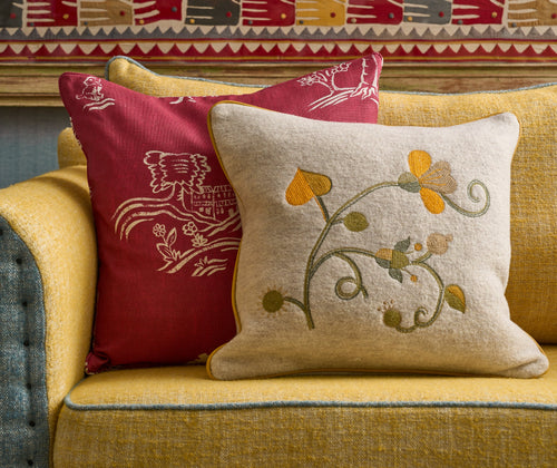 The Araminta cushion is shown lifestyle on a yellow and pale blue Willow sofa, with a Friendly Folks cushion in red 