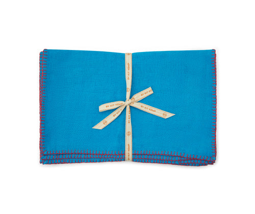 A stack of 6x turquoise linen placemats with pink blanket stitch , tied with canvas shop Kit Kemp ribbon.