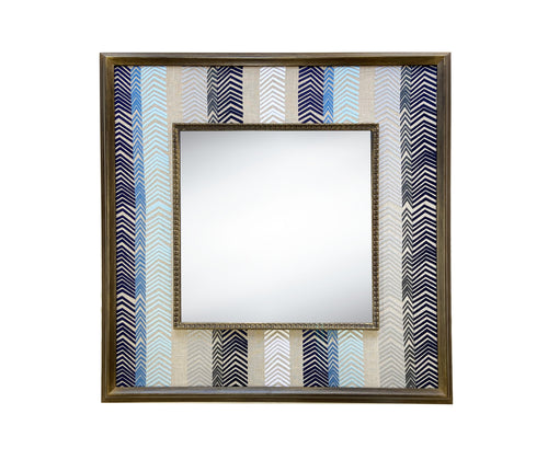 Kit Kemp's Bookend fabric for Christopher Farr with its ombre shades of blue diagonal stripes is used to stunning effect to form a wide decorative border around a square central mirror, in a wooden frame, to stunning effect.