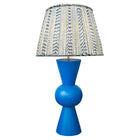 Kit Kemp's Blue Bow Lamp, makes for a striking lamp with its large sphere centre and conical upright tapered ends in a deep royal blue, this lamp base is bold in both form and colour. Topped with the gathered shade in Kit's new fabric Wriggle Room, with its white ground and zig zag stripes, in shades of blue and yellow.