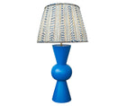 Kit Kemp's Blue Bow Lamp, makes for a striking lamp with its large sphere centre and conical upright tapered ends in a deep royal blue, this lamp base is bold in both form and colour. Topped with the gathered shade in Kit's new fabric Wriggle Room, with its white ground and zig zag stripes, in shades of blue and yellow.