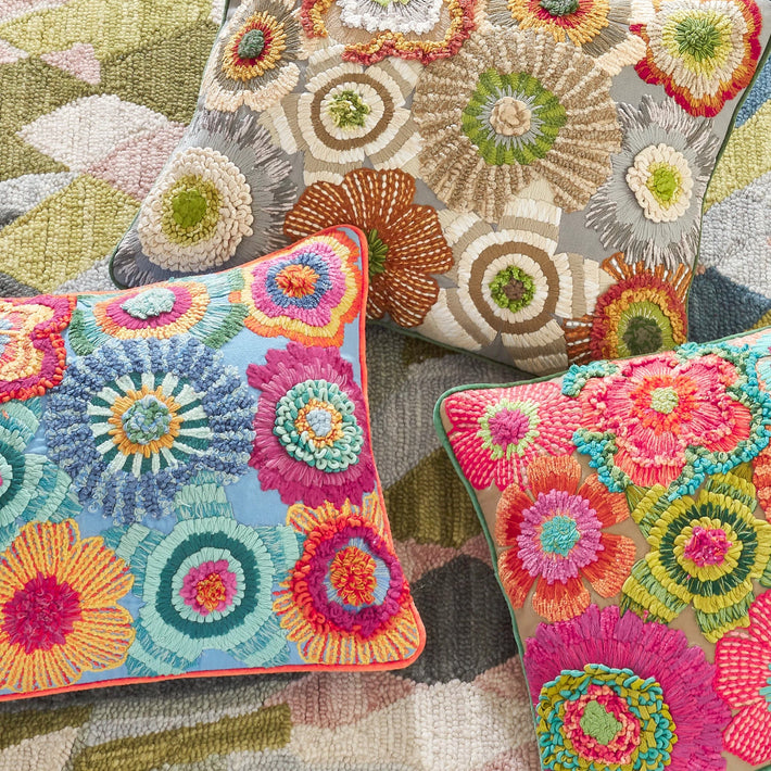 Group shot of all the colourways available in the Bramble hand embroidered Cushion, with Annie Selke. This wonderful cushion is bursting with hand embroidered florals, embellished with ribbons and boucle yarn to produce a cushions that is overflowing with design detail and colour, is available in in bright pinks, blues and oranges, and a natural option.