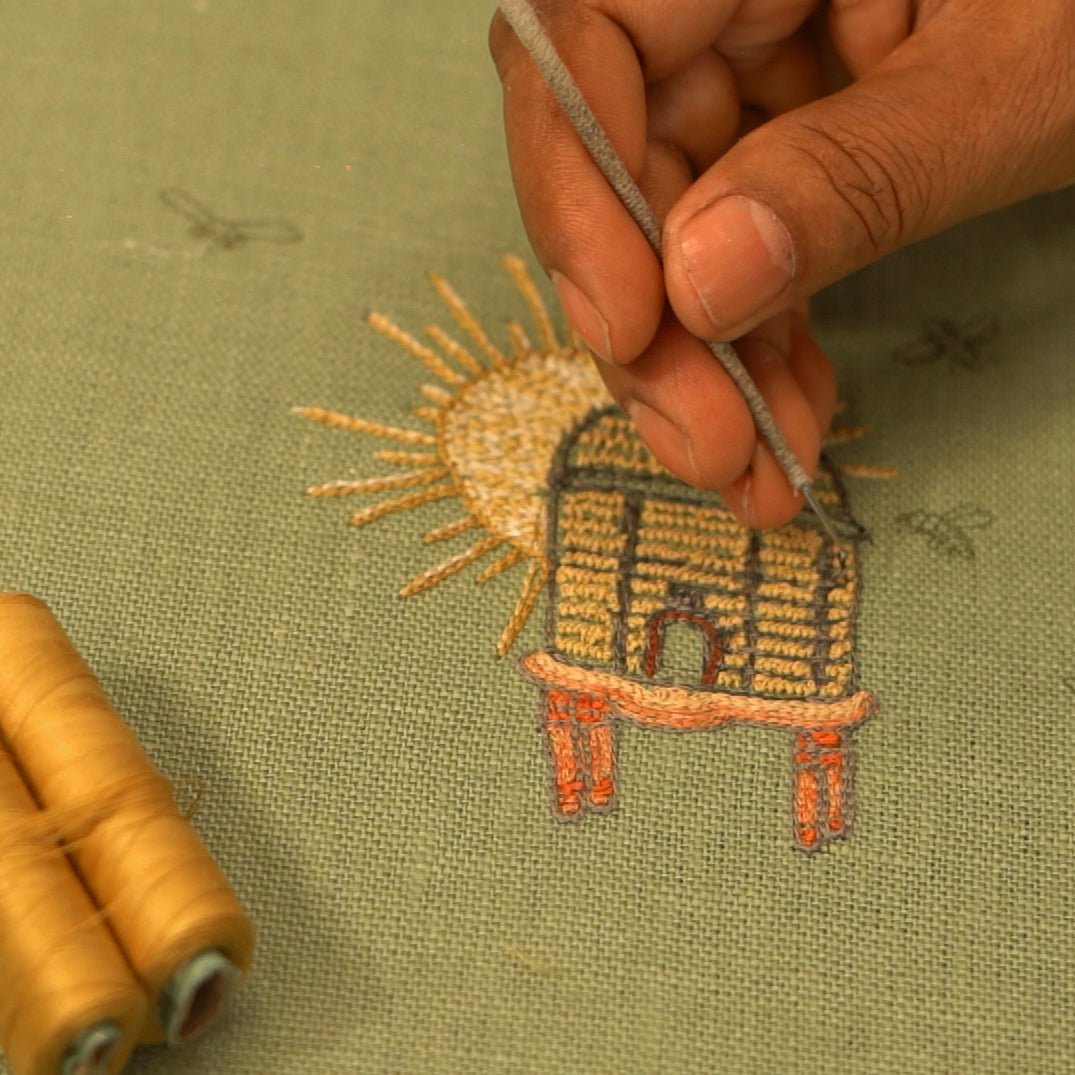 A close up of a hand stiching the Buzz Off Weekend Collection design onto a bedspread 