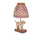 The Kit Kemp Doggy lamp is a small table lamp, consisting of a naively sculpted dog standing on the dark rectangular base of lamp, under a ruched natural linen shade with burgundy and orange stitch work forming horizontal stripes and looping patterns on the gathered shade.