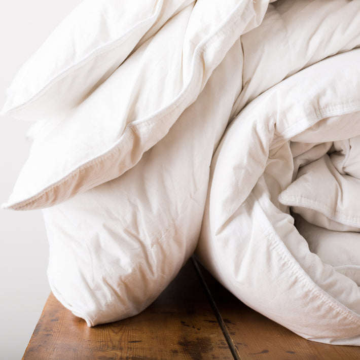 White rolled up white duvet with white cover with piped edges