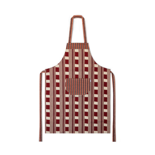 Kit Kemp's Lost and Found chequer board fabric in ruby and ecru, is made into an apron with large front pocket, shown dressed on a green mannequin.