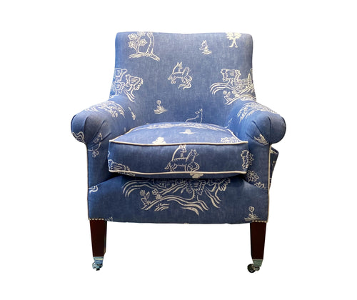 Kit Kemp's Leo arm chair , upholstered in Blue Friendly folks fabric, printed with country side scenes, and animal line drawing, in off white, viewed from the front. Seat cushion is piped in off white piping.