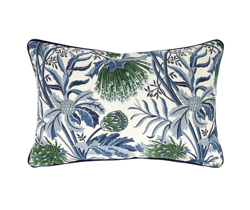 The image shows the front of the Matchstick Banksia cushion, a rectangular decorative cushion featuring a botanical print. The design includes a variety of plant elements such as leaves, branches, and specific floral patterns. The color scheme consists predominantly of blues and greens on a light, possibly white, background, highlighting the refreshing, naturalistic theme. The edges of the pillow are piped, which gives a neat and finished look.