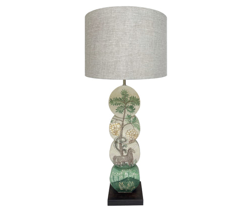 Using Kit's fabric design as inspirations the Hedgerow Quince Unicorn lamp, is hand painted by Melissa White, and features a grey unicorn, under a fruit laden tree, in muted shades of greys, greens and yellow , on a lamp base formed of 4 intersecting discs on a dark rectangular wooden base.