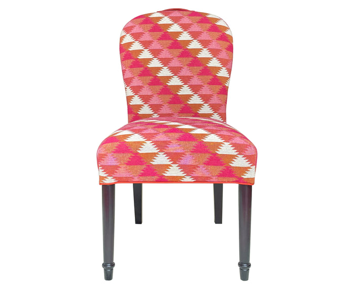 The Susan chair , with its upholstered curved back, and dark wenge wood legs is covered in the Busy Lizzy woven fabric, designed , made up of a zig zagged edged triangle in shades of pink, orange and cream, and piped in orange trim.