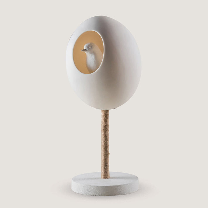 The Funky Robin Table lamp, is formed of a large porcelain egg, with an oval entrance, in which sits our funky robin ( white), lit from within, balanced on a twine wrapped steel post, and white ceramic round base. height: 320mm.