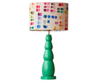 The green bobbin lamp, is a constructed out of 4 lozenge-like shapes stacked in a tower, in a bright jade green, and is dressed with Kit Kemp's mixed tones oval linen shade with its rainbow pallet of colours.