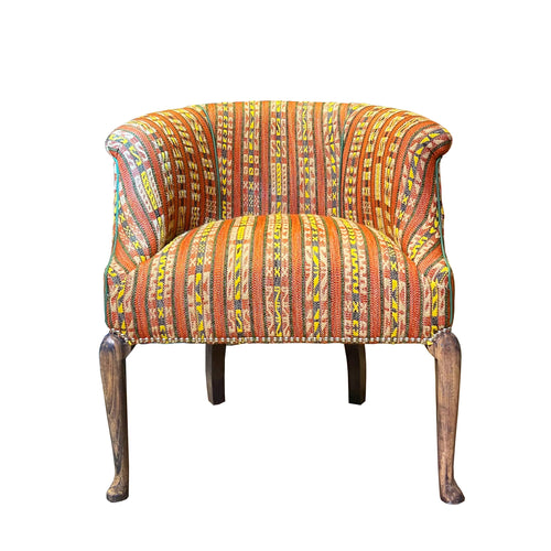 The hotline West Timber Tub chair embraces you in it's curved arms, boasts a rollover top, and elegant wooden legs. Upholstered in Kit's new Hotline fabric with Christopher Farr, it takes on an new dynamic energy, with is textured stripe effect, and intricate woven stitch, in black, and yellow detailing , on earthy terracotta toned ground. 