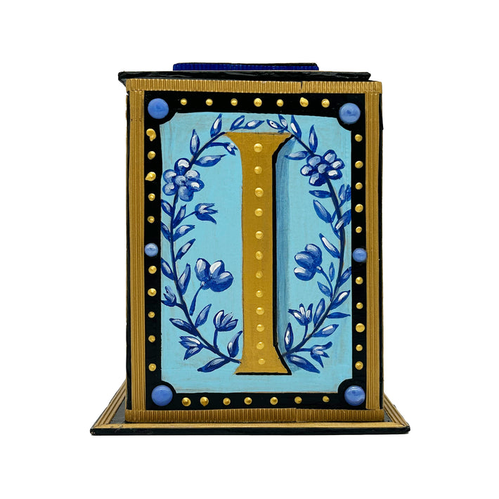 This black and gold alphabet box is decorated with a gold letter I in a heraldic decorative style, with a blue floral motif and embellished with a blue jewelled lid. 