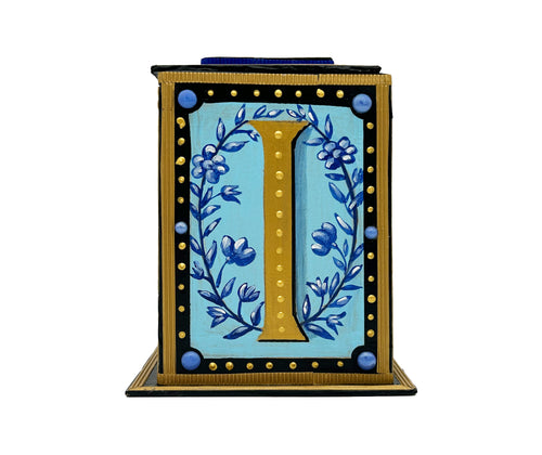 This black and gold alphabet box is decorated with a gold letter I in a heraldic decorative style, with a blue floral motif and embellished with a blue jewelled lid. 