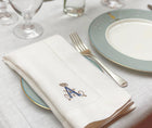 Letter A embroidered white napkin on a table cloth with plate, cutlery and glasses