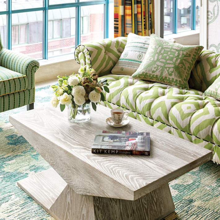 Lifestyle of Kit Kemp's Knightswood Cushion, this natural linen cutwork design is overlaid and stitched over a bright kelp green base, with a solid reverse with piped edge, is shown dressed on a green and natural sofa.