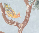 Detailed shot of the lanterns parade wallpaper in the Mid summer colourway focussing and bird in a tree in shades of mellow yellows and peaches, mauve wings, against a soft blue background.