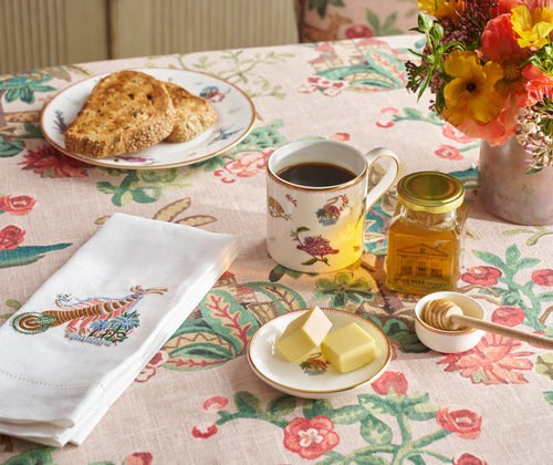 The Hyde park honey gift set is shown life styled to show the mythical creatures mug, napkin, and butter, honey dish, life-styled on a table dressed for breakfast.