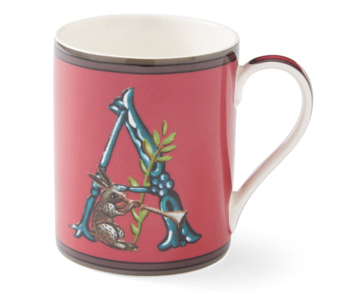 A red ceramic mug with the Initial letter A, in blue, forming a resting point for our, trumpet carrying hare, with green leaf sprig detail, red handle, and white interior. The design appears on both sides of the mug.