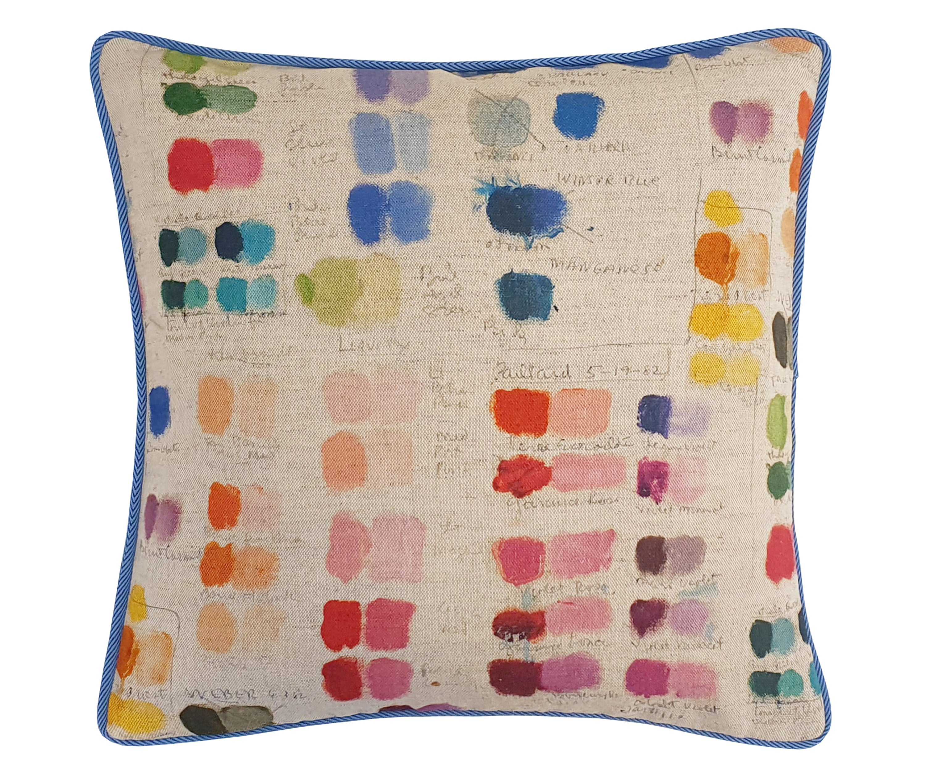 50x50 cm mixed tones cushion is made from a multi coloured fabric, featuring squares of a rainbow of colours, like a painters palette with hand written colour names, on a natural linen ground, and piped in a cornflower blue piping.