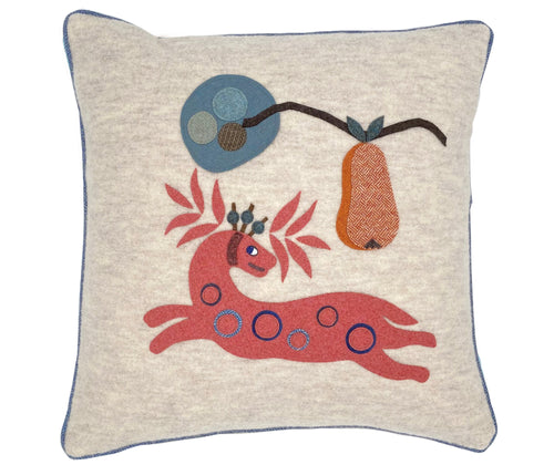 Our Pink Mythical antelope , branch-like antlers is hand appliqued onto an ecru wool cushion, piped with contrasting pale blue piping, under a branch with hanging orange herringbone wool pear.