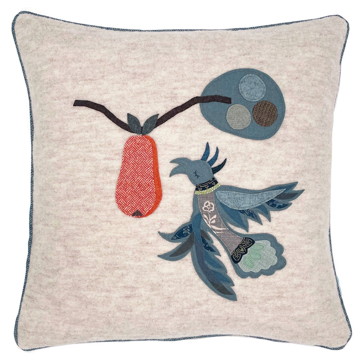 The hand appliqued Mythical Bird, in assorted shades of light blue cloth, is sewn onto a ecru wool 50x50cm cushion, next to a hanging pear, formed of orange herringbone wool.