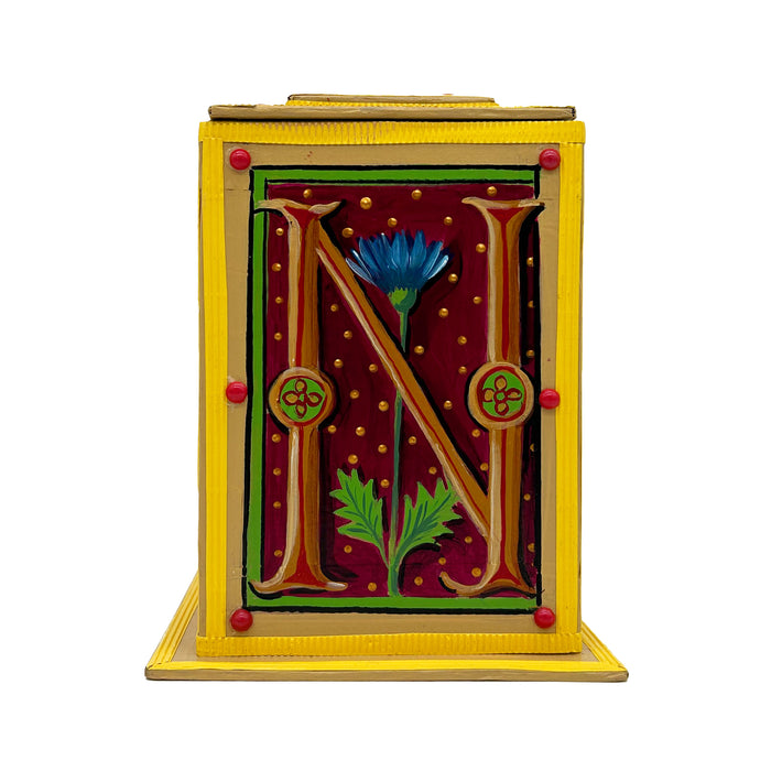 This bright yellow and red alphabet box is decorated with a gold letter N in a heraldic decorative style, with a blue floral motif and embellished with a pink and red jewelled lid. 