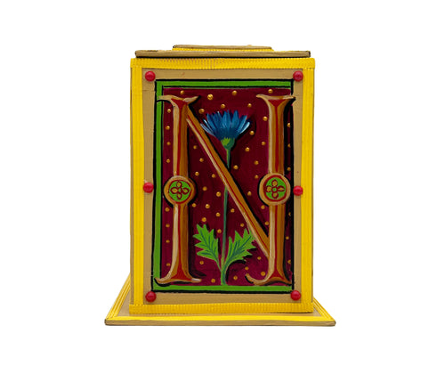 This bright yellow and red alphabet box is decorated with a gold letter N in a heraldic decorative style, with a blue floral motif and embellished with a pink and red jewelled lid. 