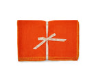 A stack of 6x orange linen placemats with yellow blanket stitch , tied with canvas shop Kit Kemp ribbon.