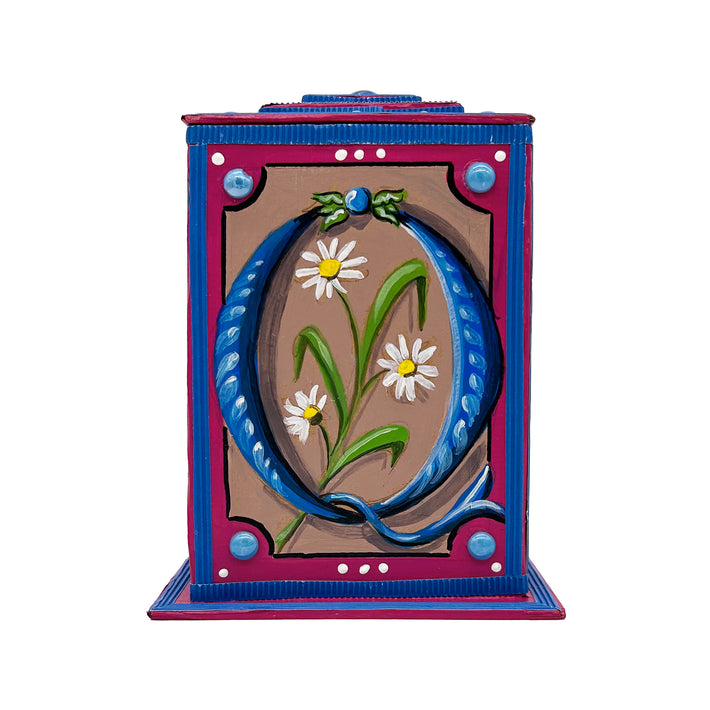 This blue and cerise alphabet box is decorated with a blue letter Q in a heraldic decorative style, with a white daisy motif and embellished with a blue and green jewelled lid. 