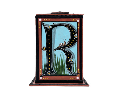 This brown and blue alphabet box is decorated with a black letter R in a heraldic decorative style, with a small snail and embellished with faux pearl jewelled lid. 