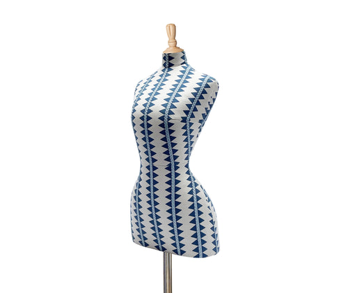 Side on view of the diamond stripe mannequin is covered in a blue and white fabric, with vertical stripes made up of horizontal blue diamonds, and over-stitched with blue cross-stitch detailing running vertically on the ecru linen ground of this mannequin, with pale wood finished stand and topper.