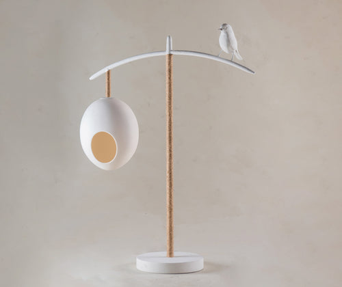 The Sleepy Robin table lamp, stands 55.5mm high, and features two suspended eggs, counter balanced on a branch like frame, softened with organic twine, with a beautifully crafted Sleepy Robin standing proudly on his branch, softened with organic twine, in white.