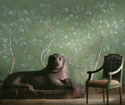 Kit's New Songbird Wallpaper has a the stylised nature of Chinoiserie landscapes with an English twist, in the Spring colourway suffused in the soft green background, where a breeze ruffles the leaves of loosely painted trees dotted with dog roses, shown with large lion sculpture in brown, and upholstered Louis 15th chair.