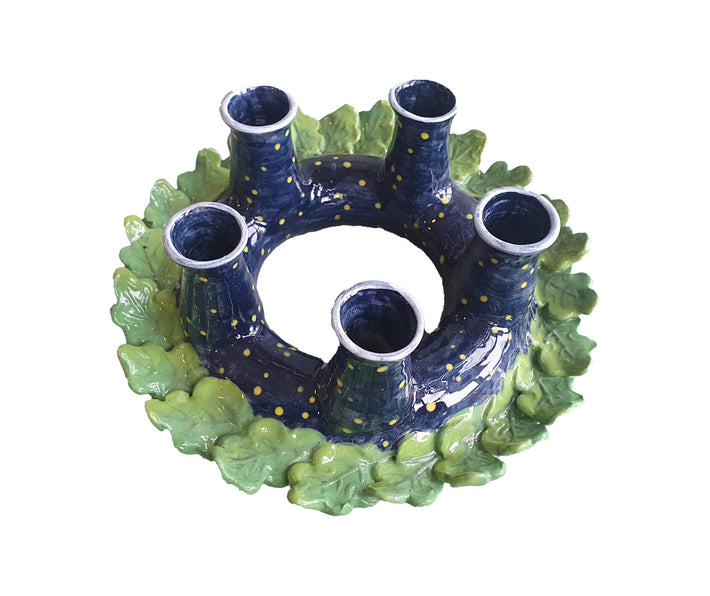 Viewed from above :Katrin Moye's Starry Oak Leaf Candle Wreath, forms a basis for 4 candle sticks, surrounded in a dark blue sky, on an overlaid leaf wreath it is a delightful centrepiece for any dining table.