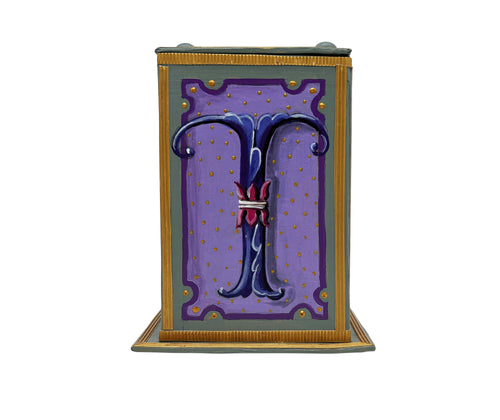 This grey and lilac alphabet box is decorated with a blue letter T in a heraldic decorative style, surrounded by a lilac starred sky, and embellished with a jewelled lid. 