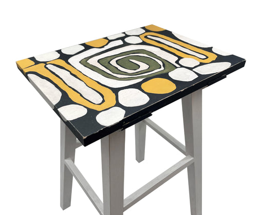 A detailed shot of the table top design consisting of a white, olive and yellow spiral design, and white splodges on a charcoal grey background.