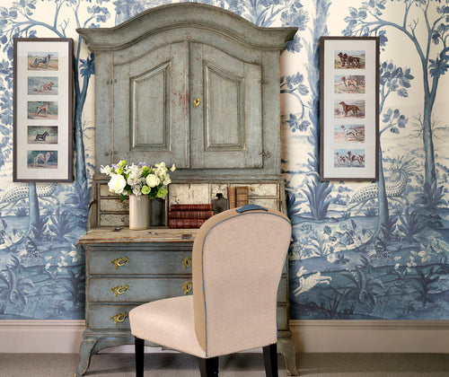 Kit Kemp's tall trees blue wallpaper , life styled with distressed blue bureau in front.